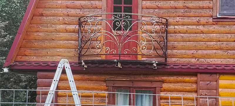 Кованый балкон с растительным орнаментом для бревенчатого дома