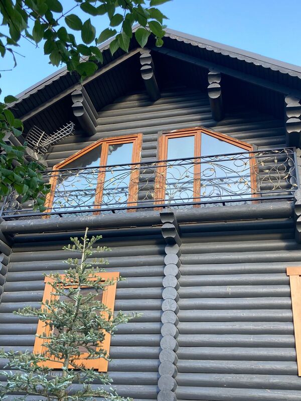 Кованый балкон с растительным орнаментом для бревенчатого дома